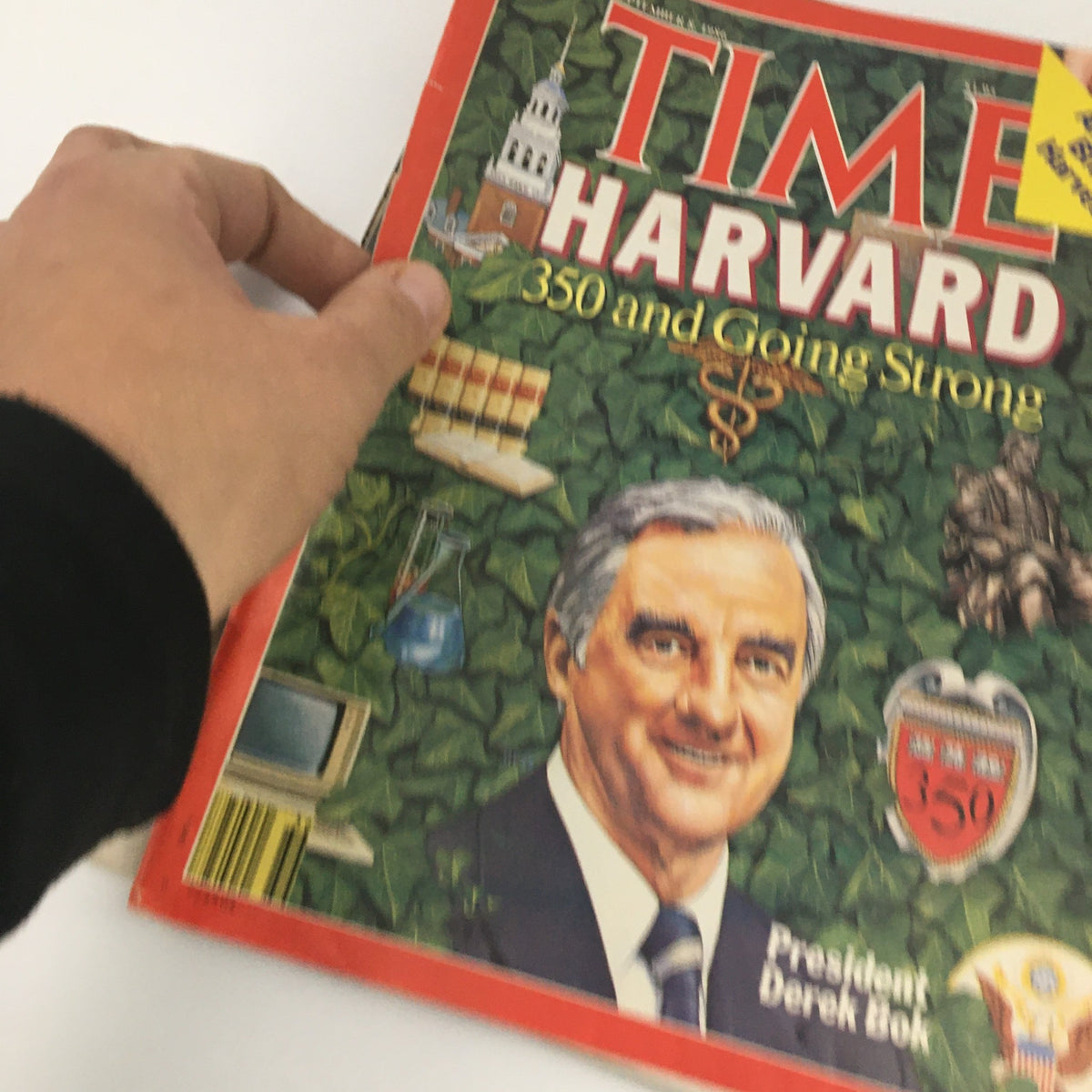 Side view of the Time Magazine from September 8, 1986, held in hand, displaying the title 'TIME HARVARD' and featured artwork related to Harvard University.