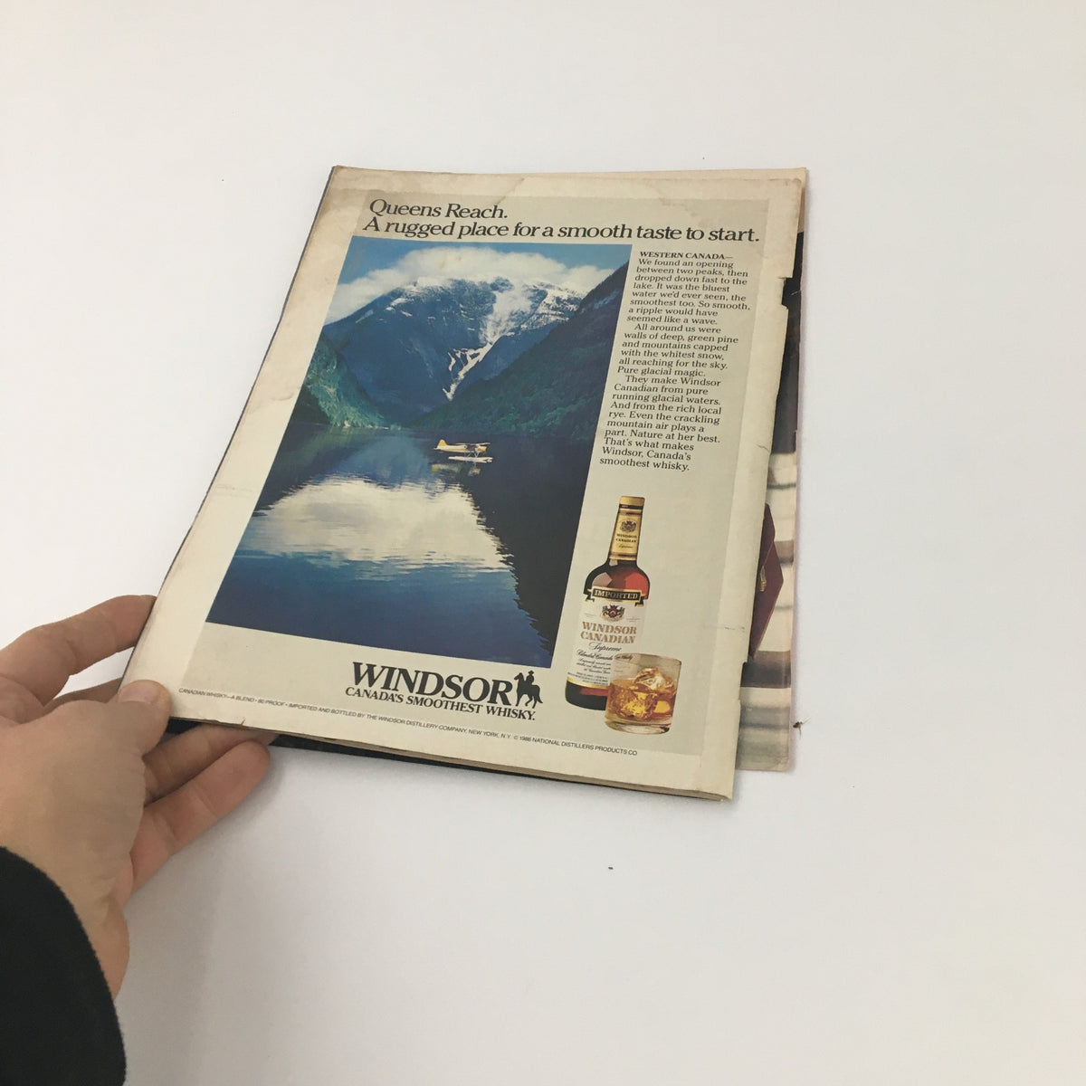 Open magazine page showing an advertisement for Windsor Canadian Whisky, with scenic imagery of Western Canada and promotional text.