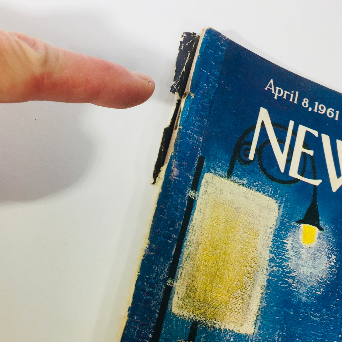 Detailed view of the spine damage on The New Yorker, April 8, 1961 edition, highlighting wear and tear, typical of vintage magazines.