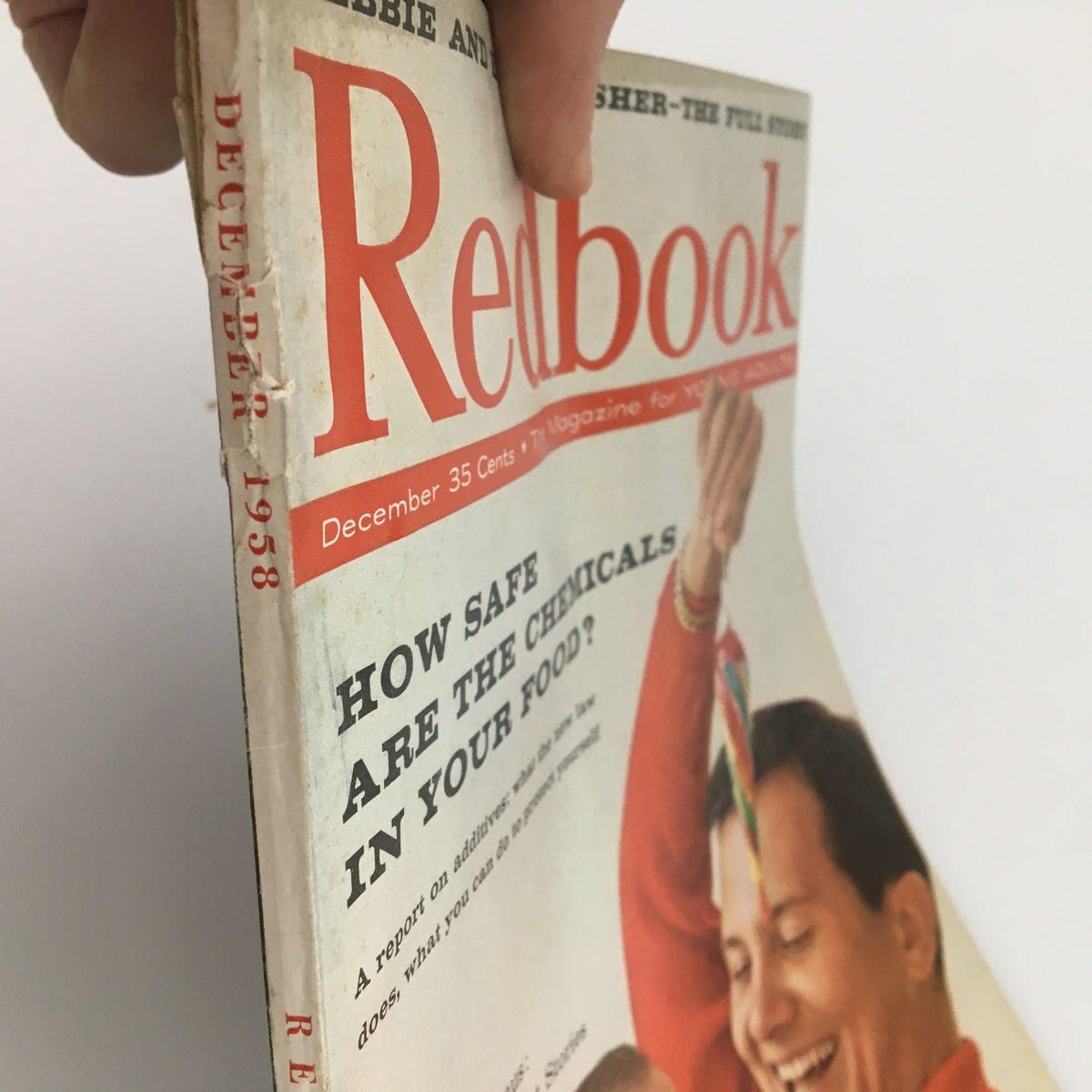 Side view of the Vintage Redbook Magazine December 1958, displaying the title and date prominently with visible wear, ideal for collectors of historical magazines.