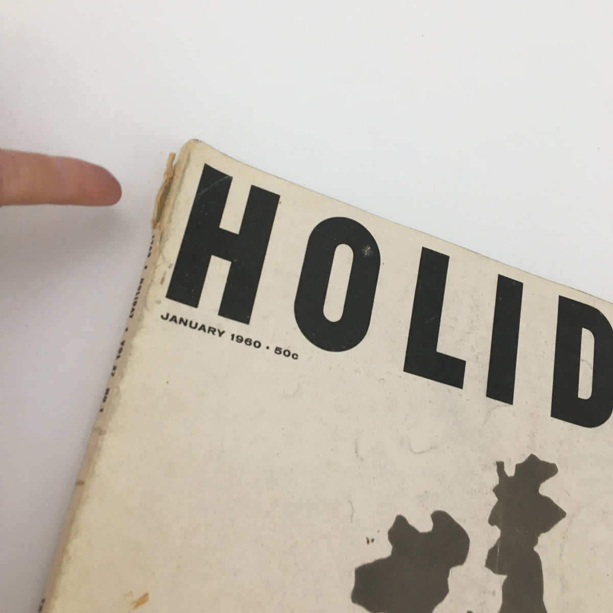 Top section of the VTG Holiday Magazine January 1960 showing the title 'Holiday' with a finger pointing at the corner, indicating wear on the magazine.