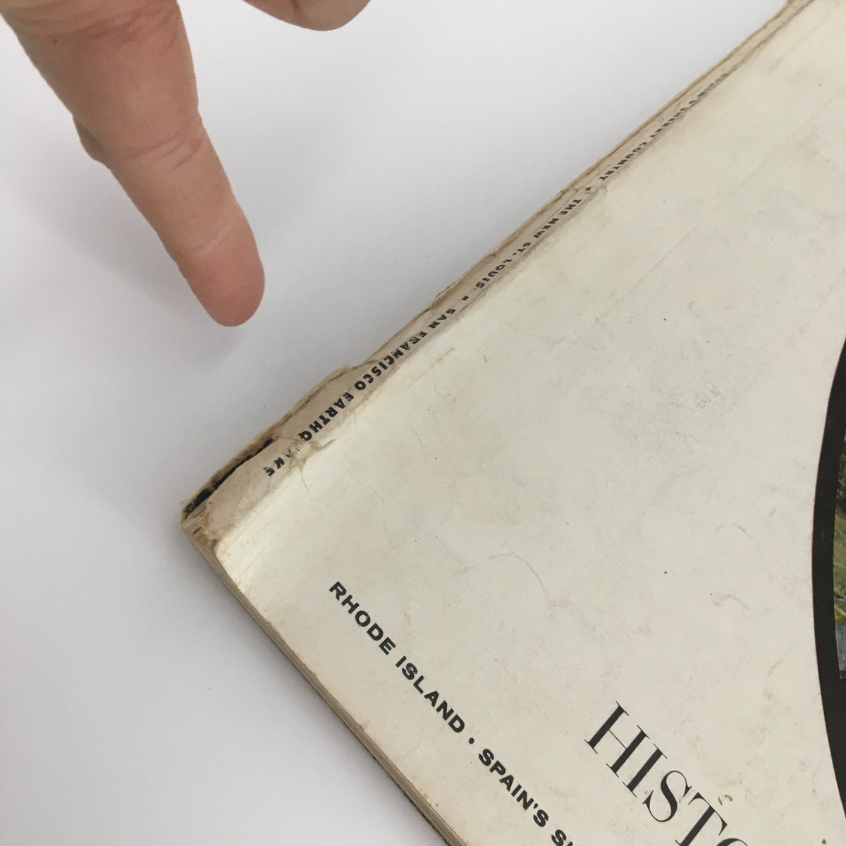 Close-up view of the edge of the VTG Holiday Magazine May 1960, featuring historic Scotland on the cover. Showcasing the magazine's spine with visible wear and a pointing finger indicating condition details.