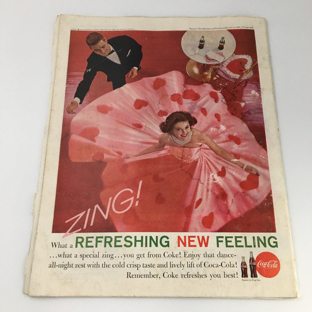 Advertisement page from The Saturday Evening Post February 11, 1961 showcasing a vibrant Coca-Cola advertisement with a woman in a heart-themed dress, emphasizing vintage charm.