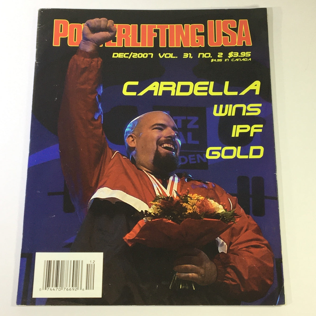 Powerlifting USA December 2007 Vol 31 #2 featuring Tony Cardella celebrating his gold medal win at the IPF World Championships. The magazine cover displays Cardella with a bouquet of flowers, showcasing his victory in powerlifting.