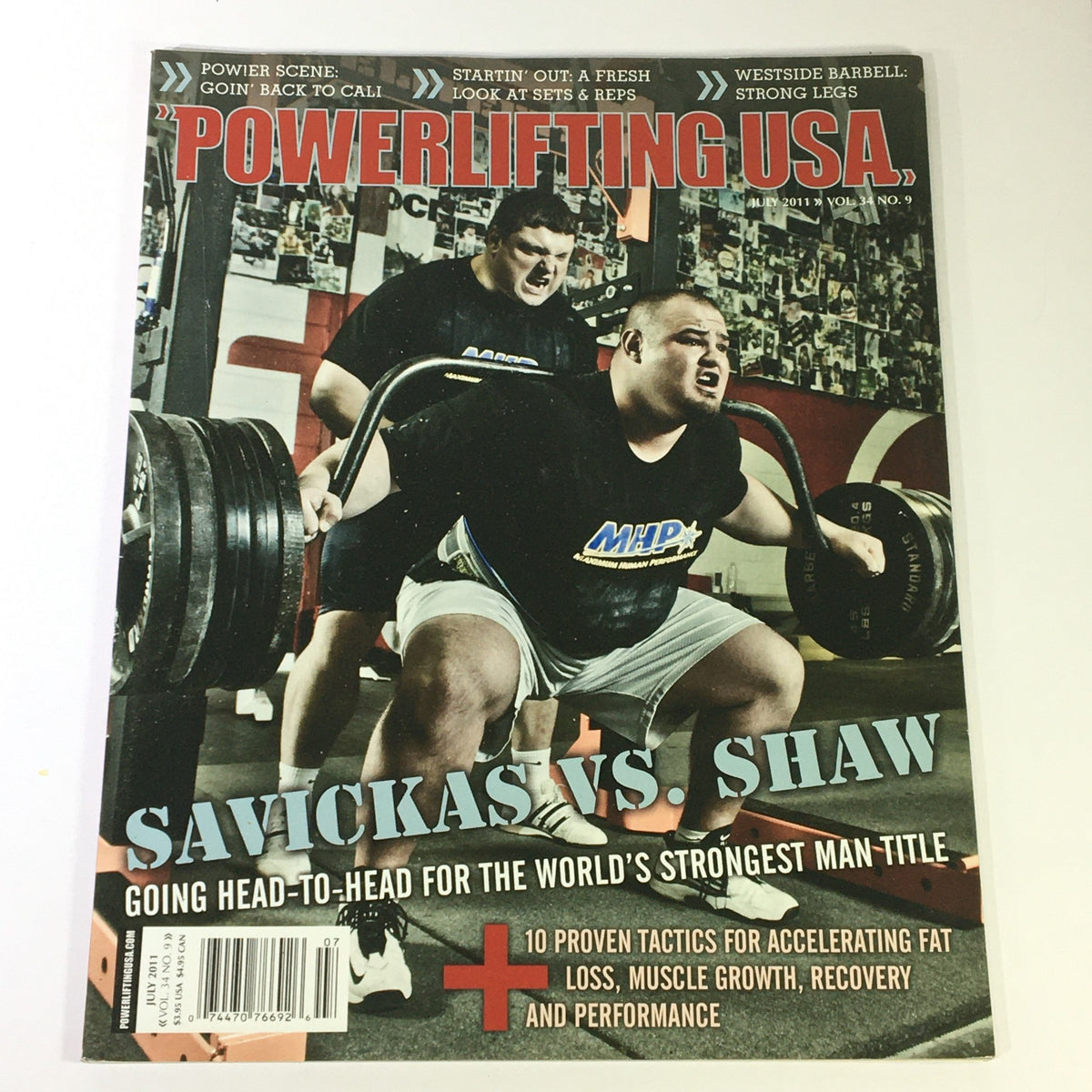 Cover of Powerlifting USA July 2011 Vol 34 #9 featuring a dramatic showdown between Žydrūnas Savickas and Brian Shaw, showcasing intense powerlifting action with a strong focus on the competition atmosphere.