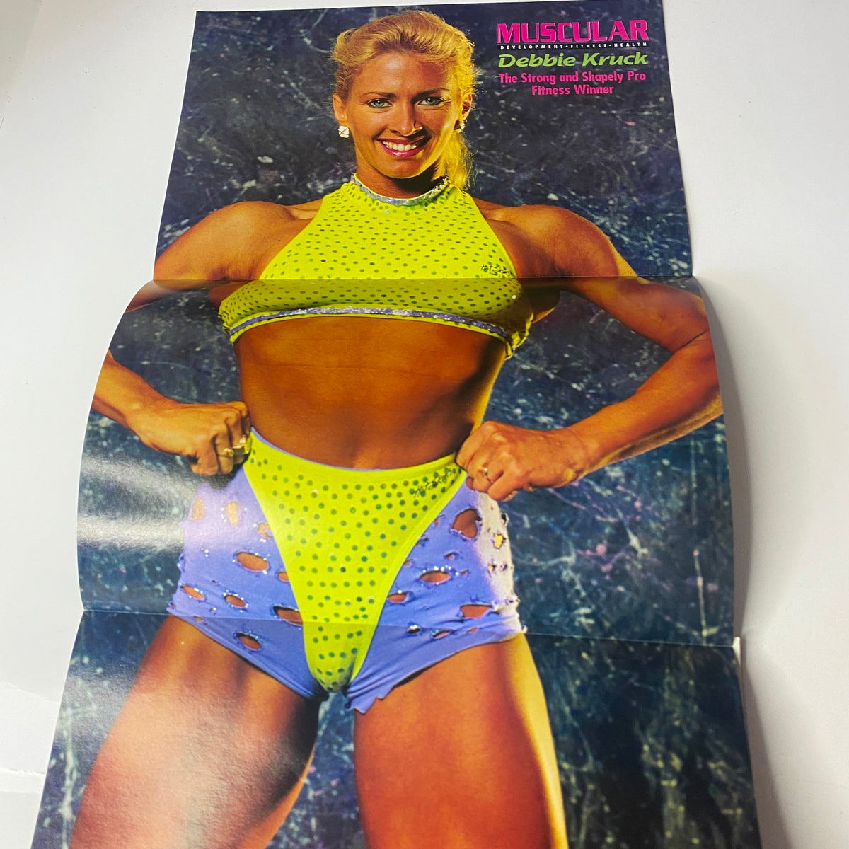 Muscular Development Magazine May 1994 featuring a poster of Debbie Kruck, a fitness model, showcasing a vibrant workout outfit with cut-out shorts. This magazine captures the essence of 1990s bodybuilding culture.