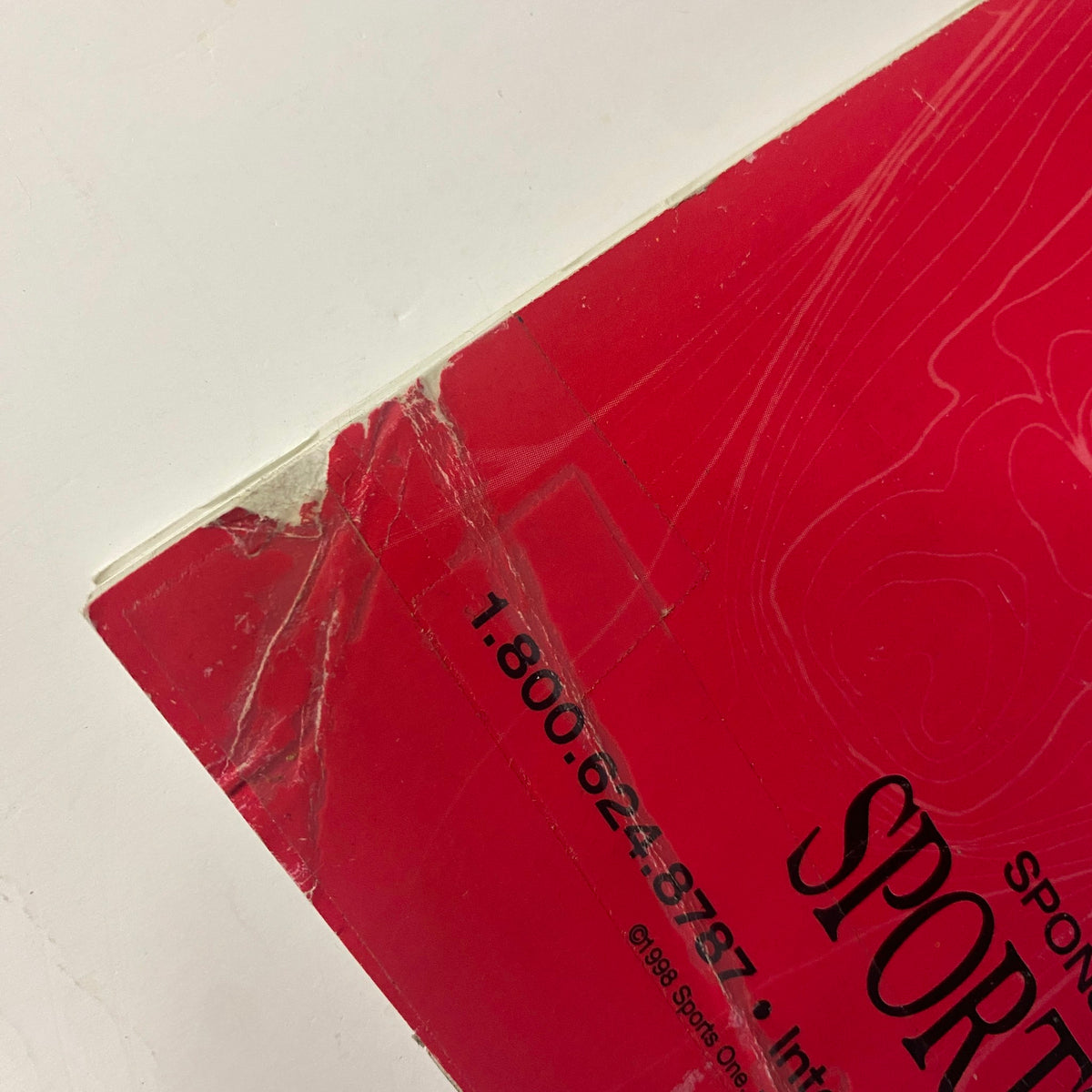 Close-up of the back cover damage of Muscular Development Magazine January 1999, showing a repaired tear along the edge.