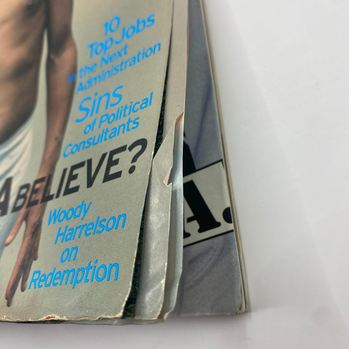 Close-up view of the edge of George Magazine December 1996, highlighting wear and tear, yet preserving the iconic title featuring Woody Harrelson.
