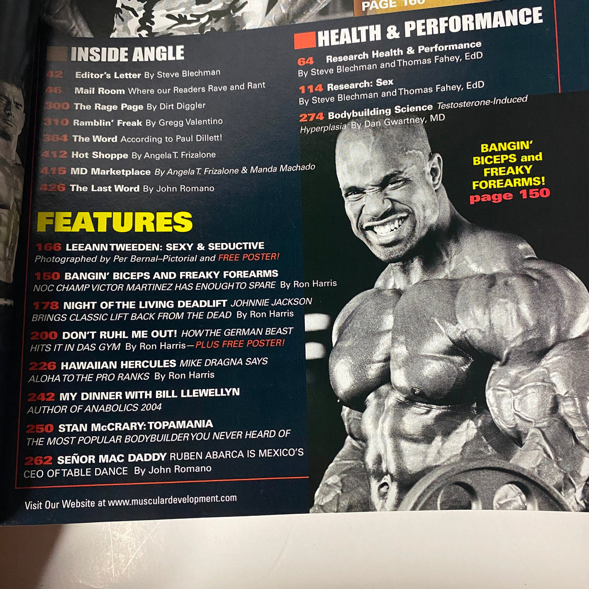 Features page from Muscular Development Magazine December 2003 listing notable articles and interviews, including Leeann Tweeden and Victor Martinez, emphasizing free posters and training insights.