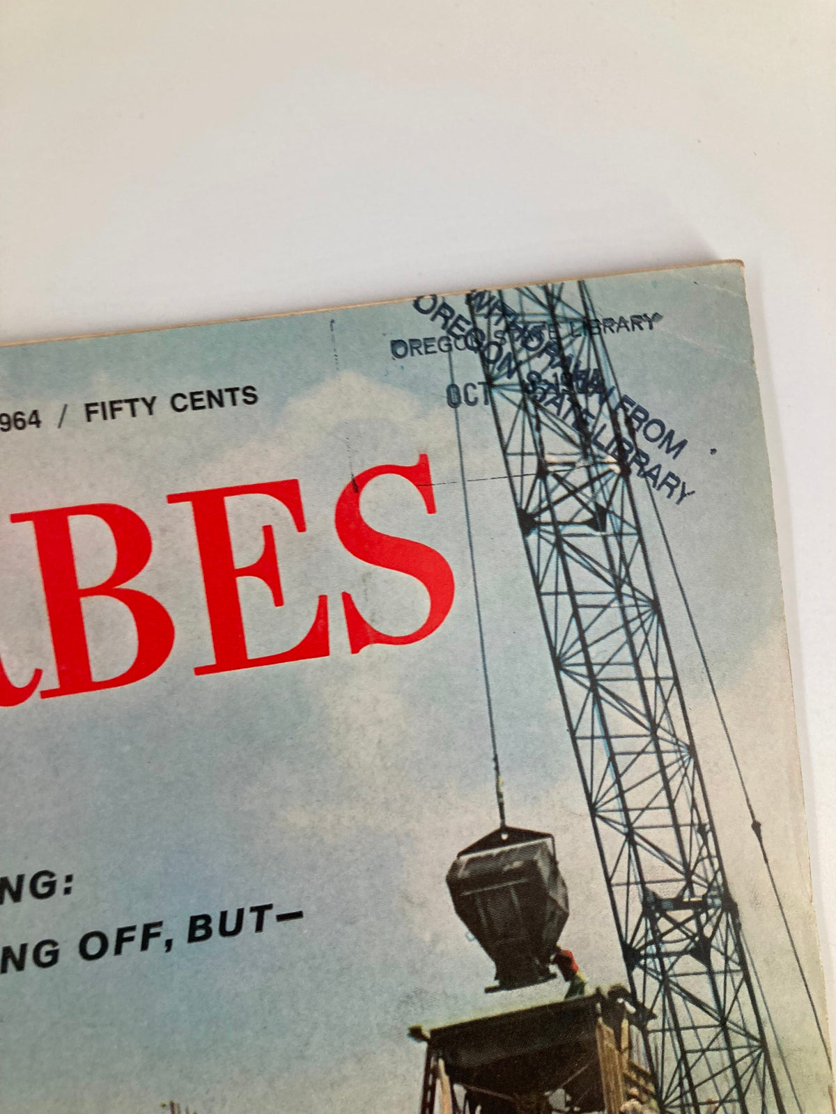 Close-up of the top corner of the VTG Forbes Magazine October 1, 1964 cover showcasing its date and title, including a detail of the construction crane.