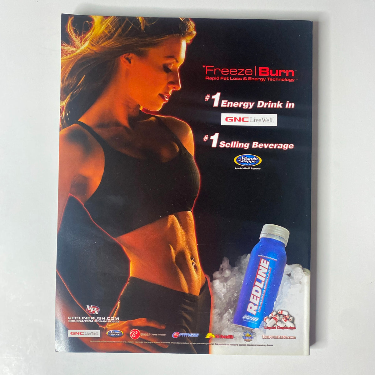 Promotional advertisement for Redline 'Freeze | Burn' energy drink, showcasing its popularity as a top-selling product, featured in Muscular Development Magazine April 2006.
