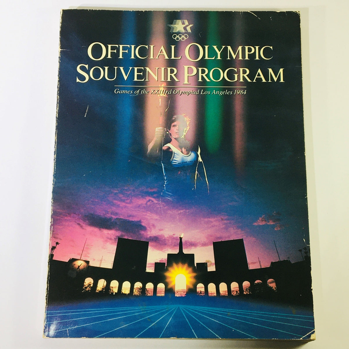 Cover of the Official Olympic Souvenir Program 1984 - Games of XXIIIrd Olympiad Los Angeles, featuring a vibrant design with an athlete and sunset background.
