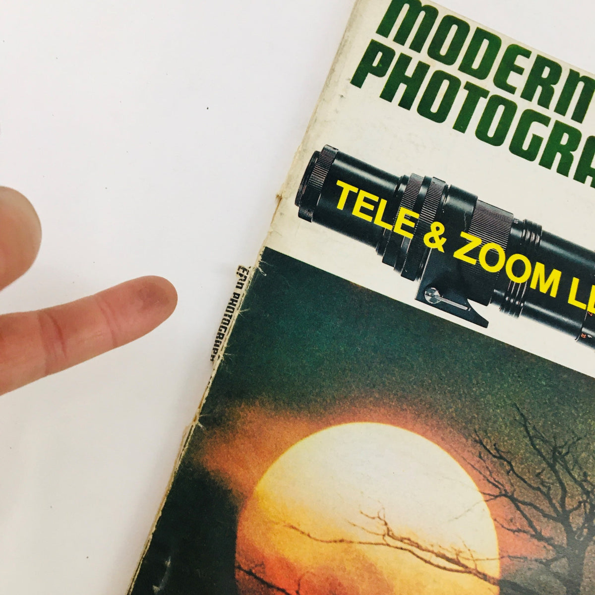 Side view of Modern Photography Magazine August 1970 showing a finger pointing towards the 'Tele & Zoom Lens Special' title, highlighting its vintage appeal for collectors.