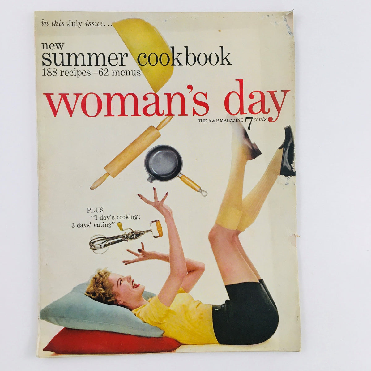 Cover of Woman's Day Magazine July 1954 featuring the title and imagery related to summer cooking, showcasing a woman playfully interacting with kitchen utensils.