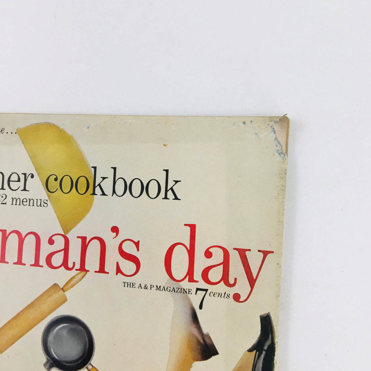 Close-up view of the cover of Woman's Day Magazine July 1954 highlighting the title and summer cookbook information along with vintage kitchen tools.