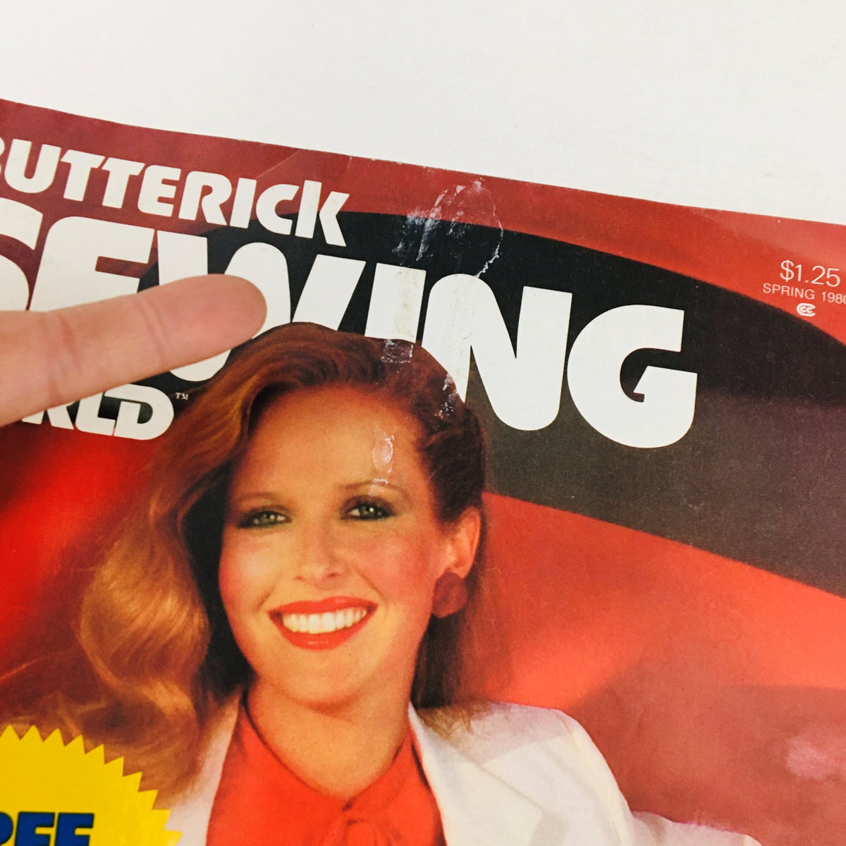 Close-up of the cover of Butterick Sewing World Magazine Spring 1980, showcasing the title and a model's smiling face, emphasizing the vintage style and free pattern announcement.