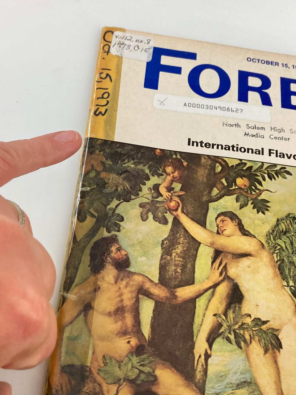 Close-up view of the cover of VTG Forbes Magazine October 15, 1973 titled 'Cashing In on Mankind's Oldest Instincts' with fingers pointing at the title.