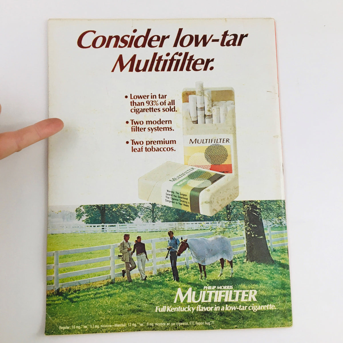 Back cover advertisement of Philip Morris Multifilter cigarettes, highlighting its low tar content and modern filter systems, showcasing a serene outdoor scene with people and a horse.