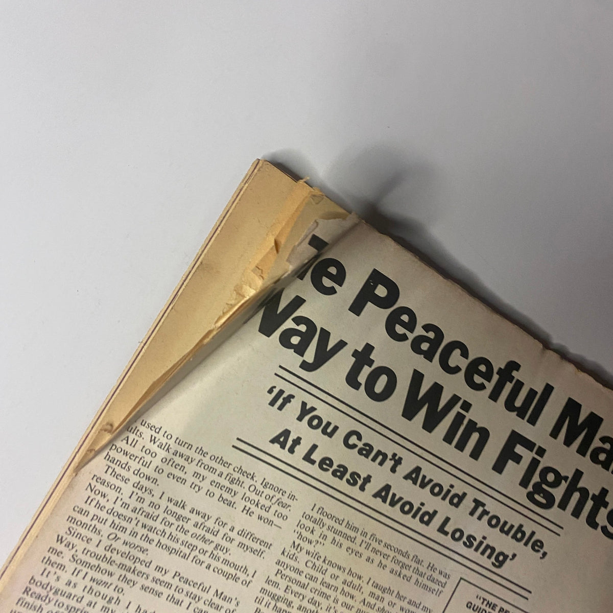 Detailed view of the top corner of 'The Peaceful Man’s Way to Win Fights' article from Muscle & Bodybuilder Magazine March 1981, showing edge damage and textual content about avoiding trouble in conflict.