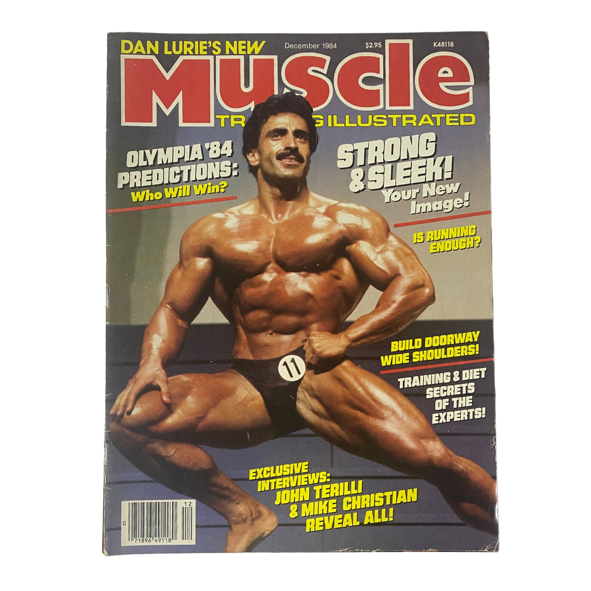 Cover of Muscle Training Illustrated December 1984 issue No. 118 featuring Samir Bannout showcasing a muscular physique and posing with the headline 'Olympia '84 Predictions: Who Will Win?' highlighting bodybuilding content.