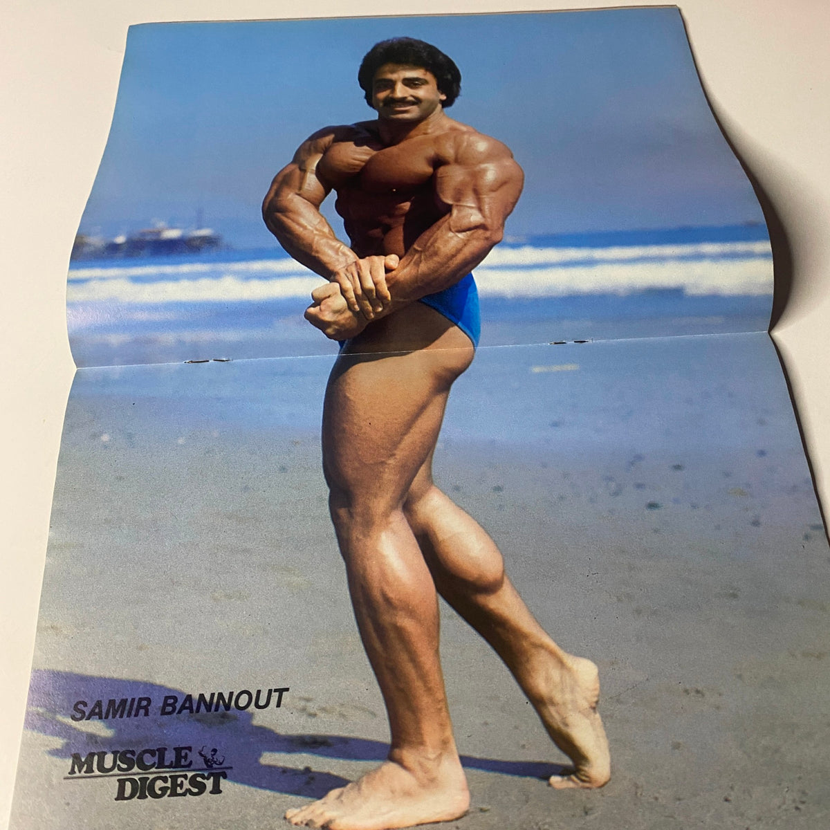 Samir Bannout posing at the beach featured in the Muscle Digest Magazine April 1982 Vol 6 No. 3, showcasing his impressive physique.
