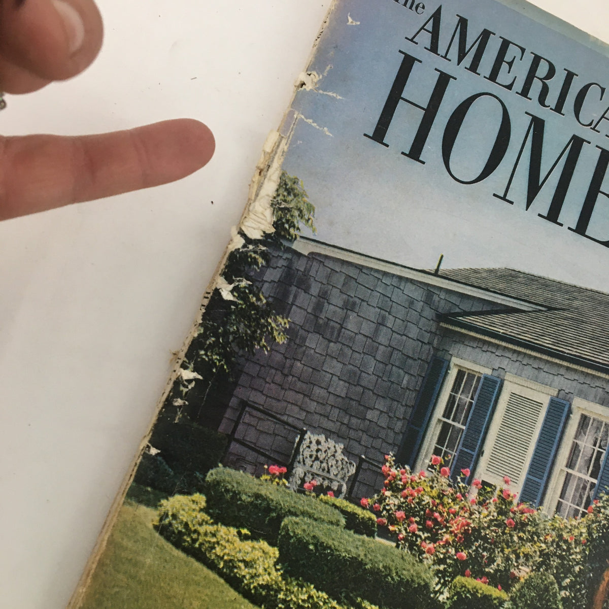 Detail of the cover of The American Home Magazine April 1951, showing the top left corner with finger pointing at the magazine's torn edge.