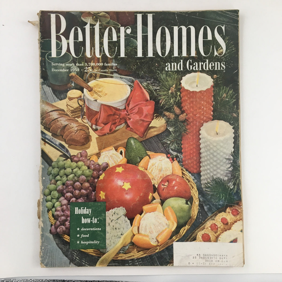 Cover of Better Homes & Gardens December 1953 magazine featuring a holiday spread with traditional foods and decorations, highlighted by a basket of fruits and a centerpiece of candles.