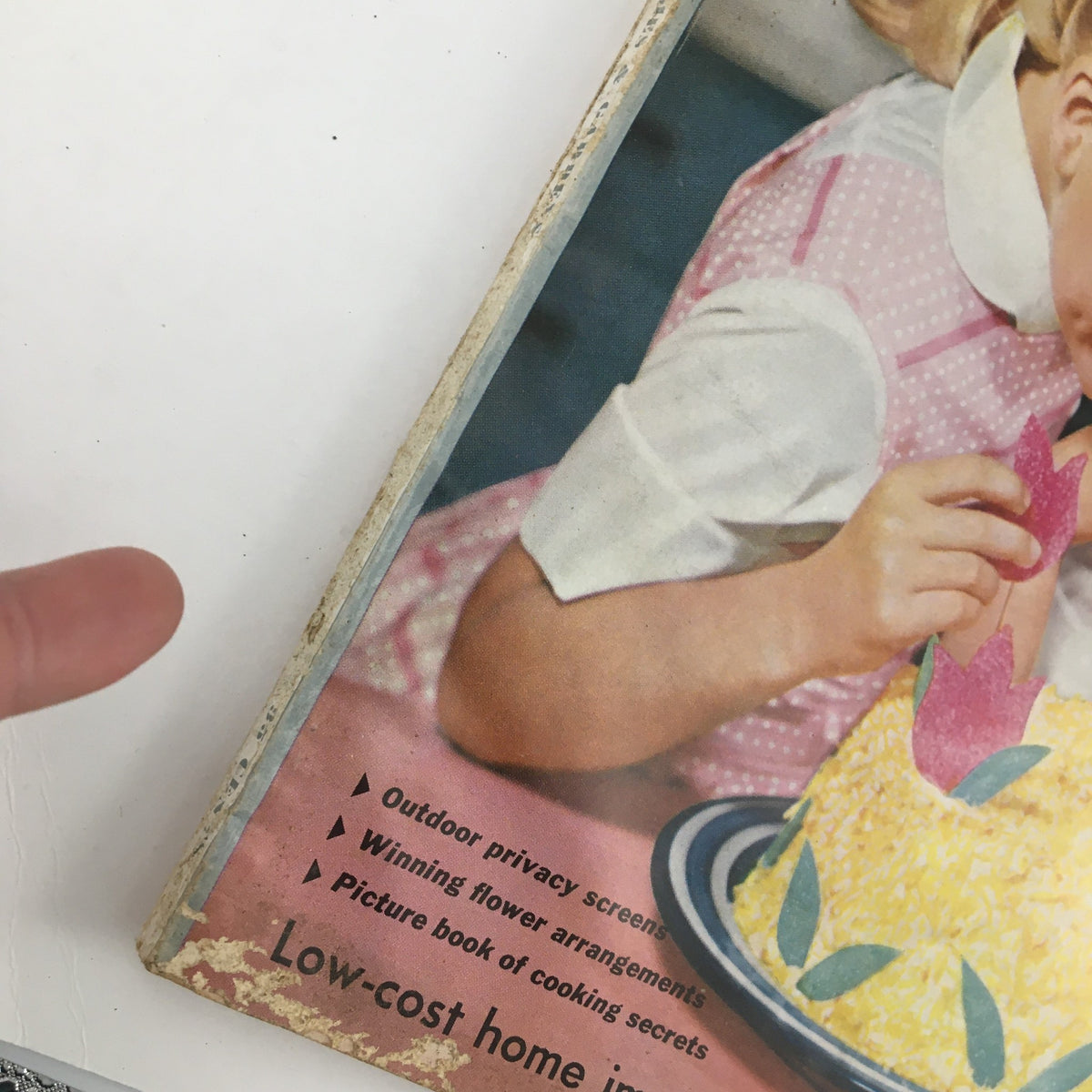 Close-up view of the side of Better Homes & Gardens March 1958 magazine, focusing on the cover details including the colorful cake decoration, promoting the article on cheese dishes.