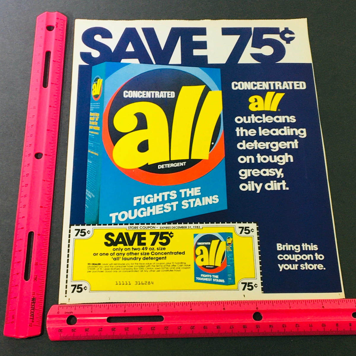 VTG Retro 1983 All Concentrated Detergent ad displaying a product box and a savings coupon for 75 cents, against a dark background with a measuring ruler for scale.
