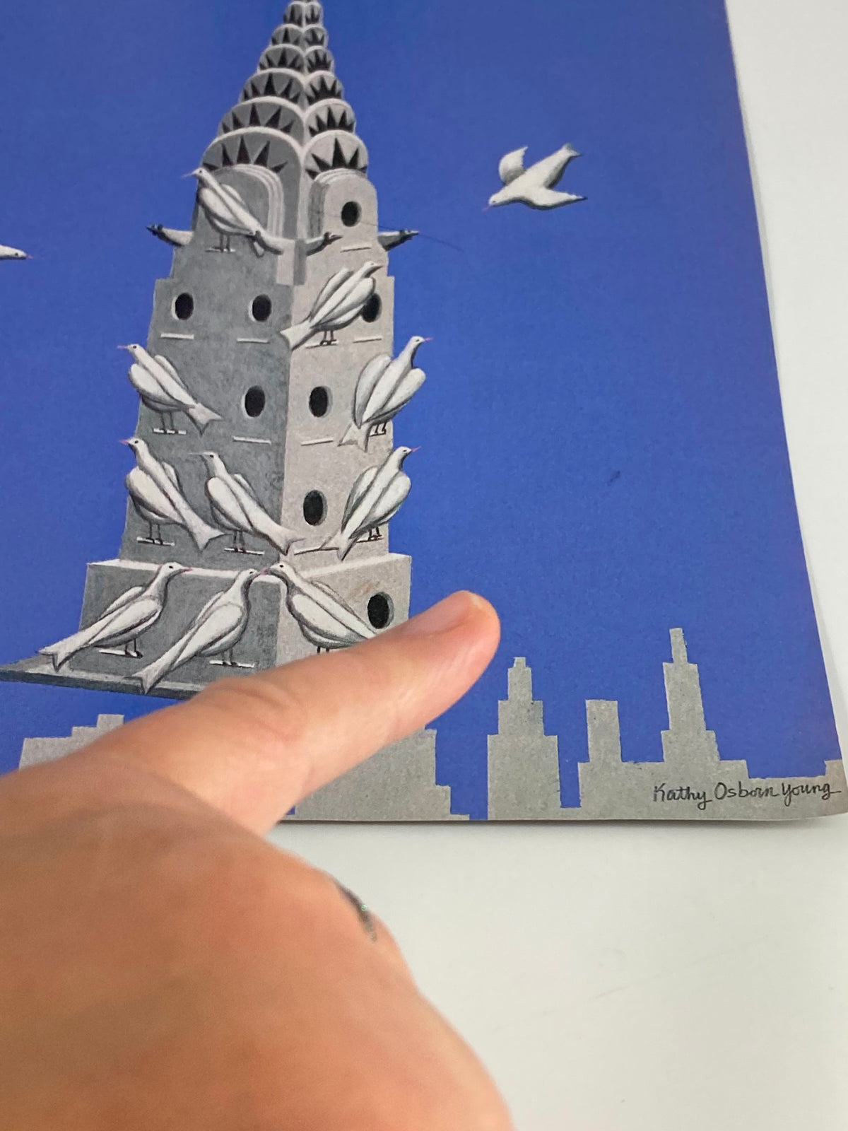 Detailed view of The New Yorker cover from May 8, 1989, showcasing the artistic birdhouse design by Kathy Osborn Young, with a finger pointing at the artwork, exhibiting its intricate details.