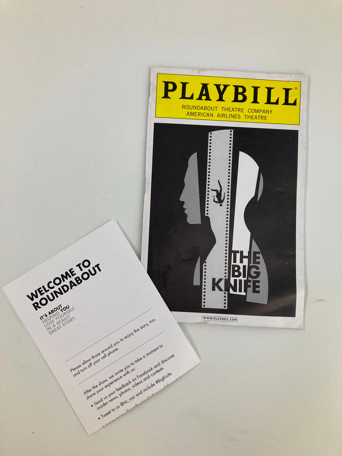 2013 Playbill for The Big Knife by Clifford Odets featuring a dramatic black and white design, displayed alongside a welcome card from Roundabout Theatre Company, American Airlines Theatre.