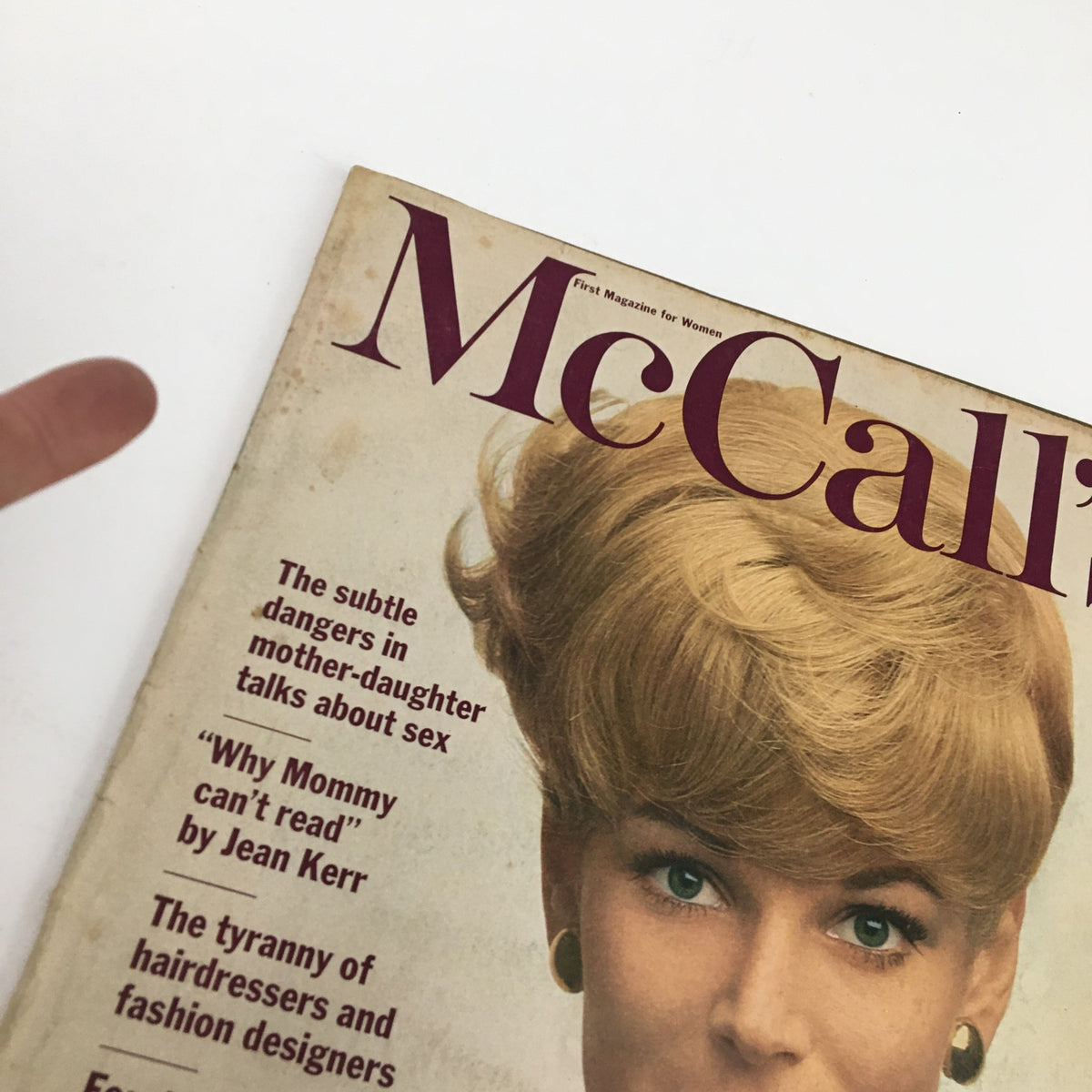 Close-up of McCall's Magazine January 1966 cover showing a woman with a bouffant hairstyle and a polka dot bow tie, with article titles visible, representing vintage fashion and culture.