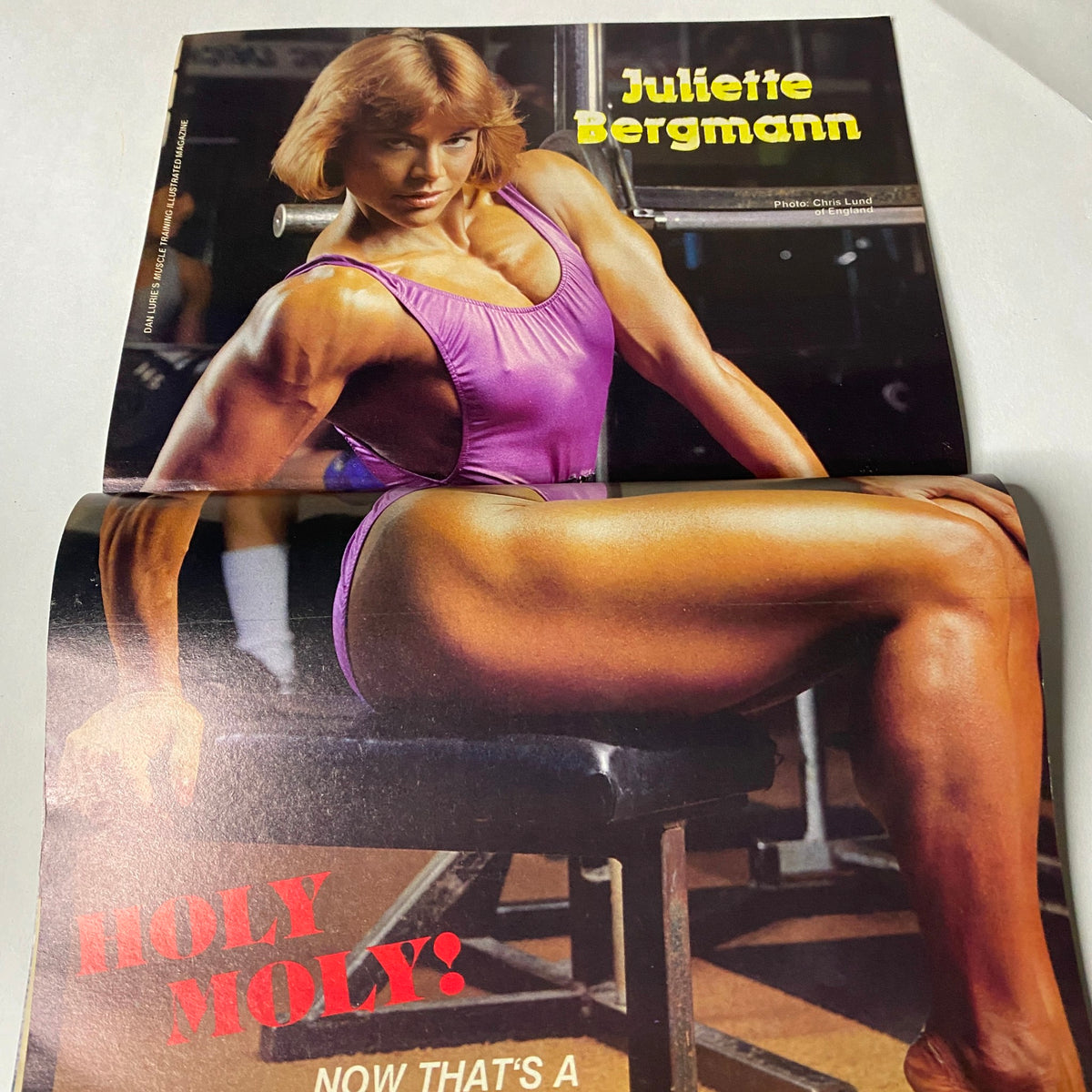 Centerfold from Muscle Training Illustrated December 1986 featuring Juliette Bergmann in a striking pose. The magazine highlights her impressive physique with vibrant colors and text promoting her strength and excellence in bodybuilding.