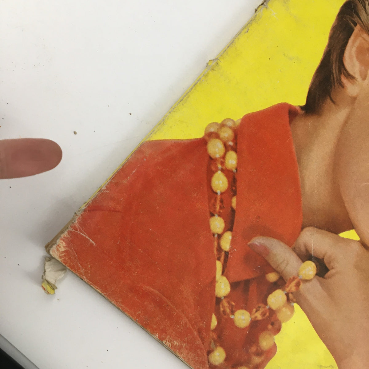 Close-up image showing the edge of McCall's Magazine, October 1954, highlighting wear and a finger pointing to the vintage cover.
