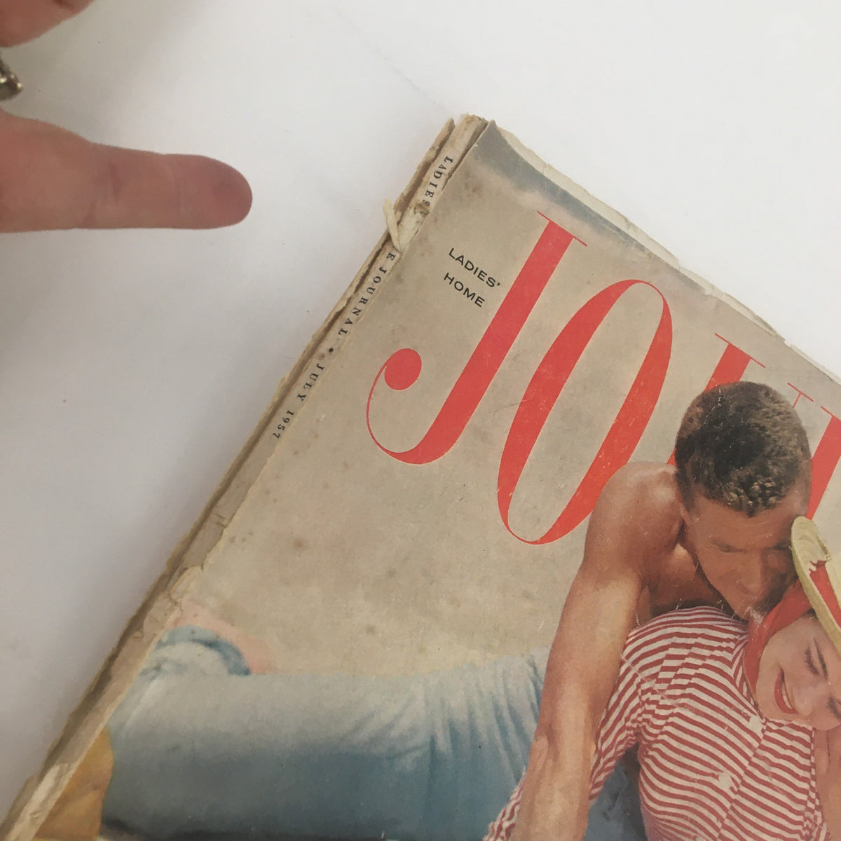 Close-up view of the spine and title of Ladies' Home Journal Magazine July 1957, showcasing vintage magazine wear and tear.