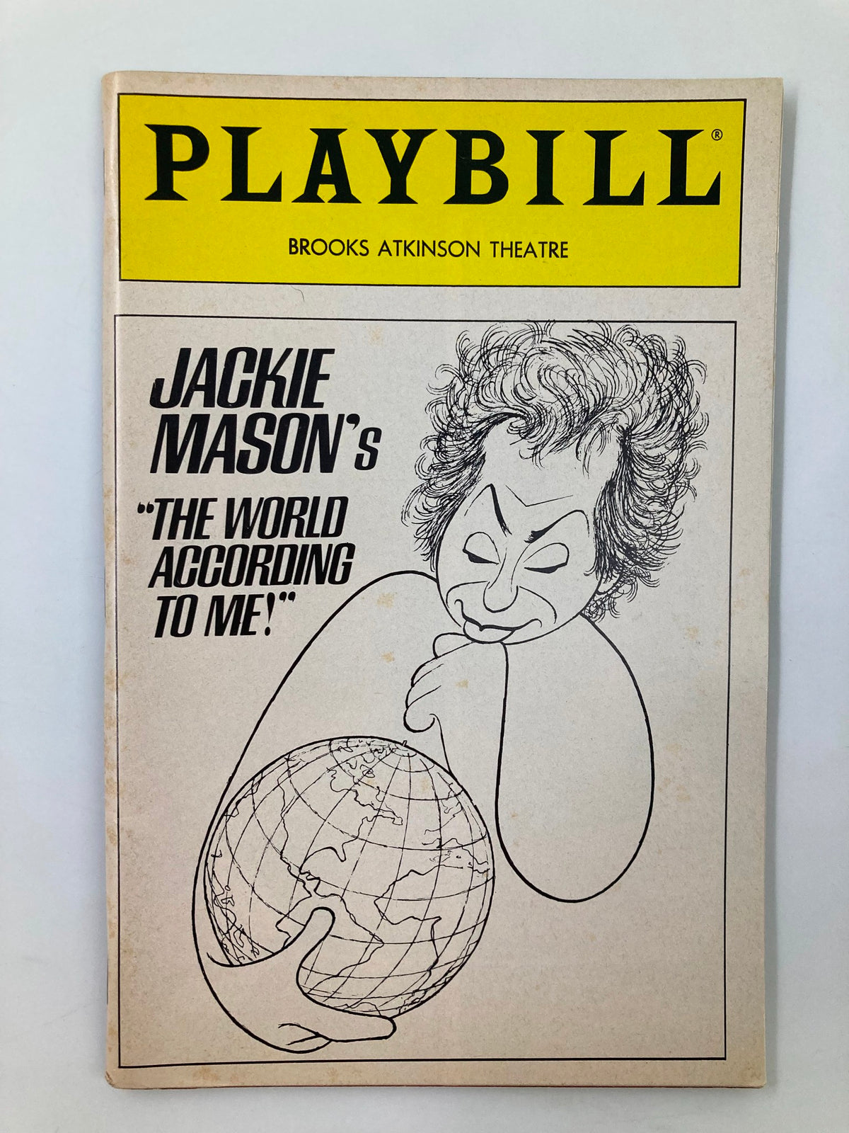 1988 Playbill for Jackie Mason's The World According To Me! featuring a caricature of Jackie Mason holding a globe, showcasing the vibrant cover design from the Brooks Atkinson Theatre.