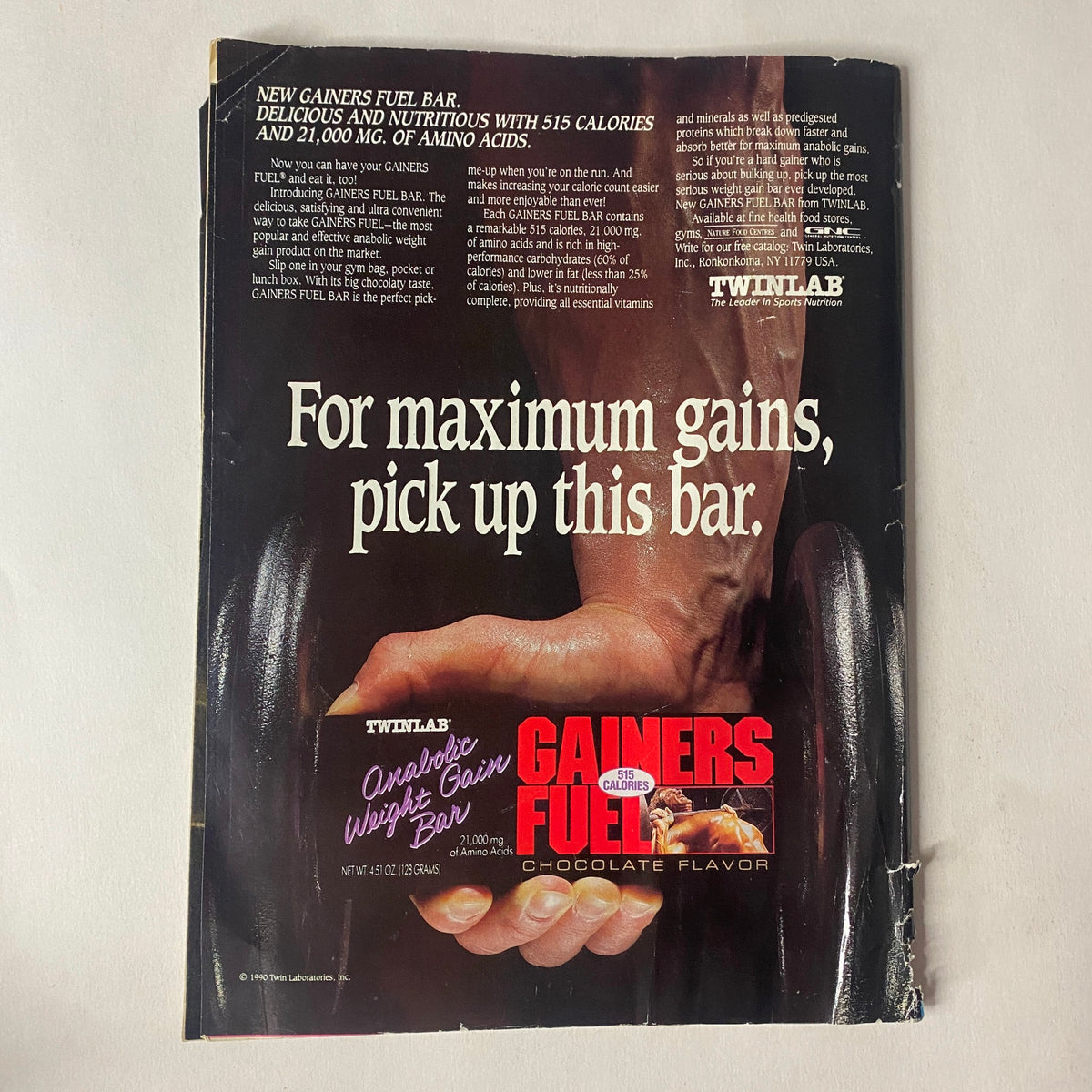 Advertisement for Twinlab Gainers Fuel Bar featured in Muscle Training Illustrated July 1991 Vol 166 by Steve Brisbois and Elaine Tarantin. The ad promotes the bar's high-calorie content and nutritional benefits for muscle gains.