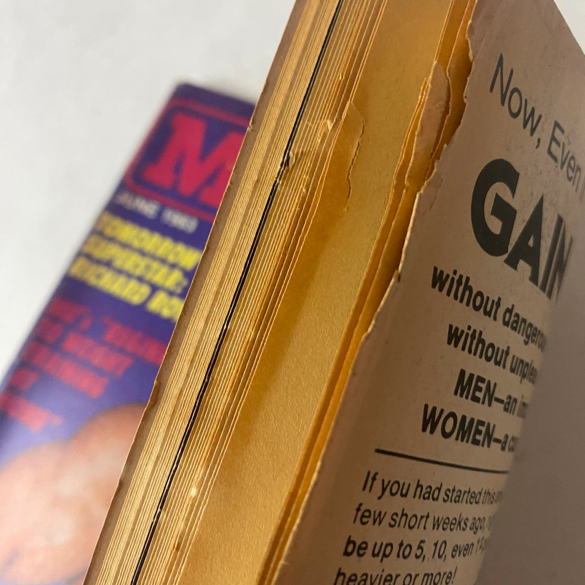 Page showing the edge of Muscle Up Magazine June 1983 Vol 5 No 23 featuring a worn spine with yellowing pages, indicating its vintage nature.