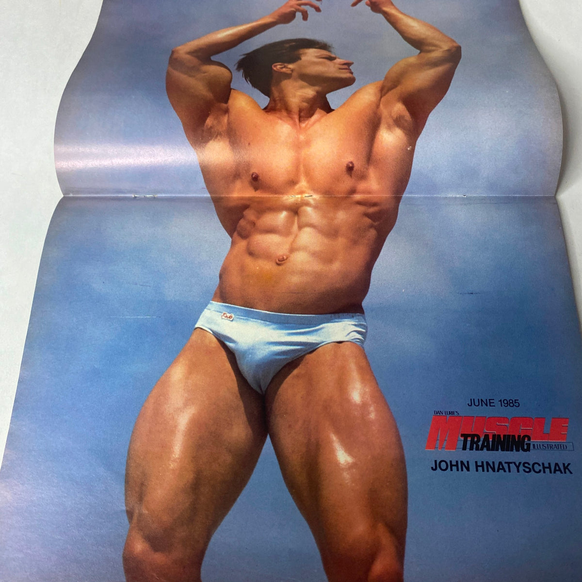 Centerfold of John Hnatyschak from Muscle Training Illustrated June 1985, showcasing a muscular pose and classic bodybuilding aesthetics.