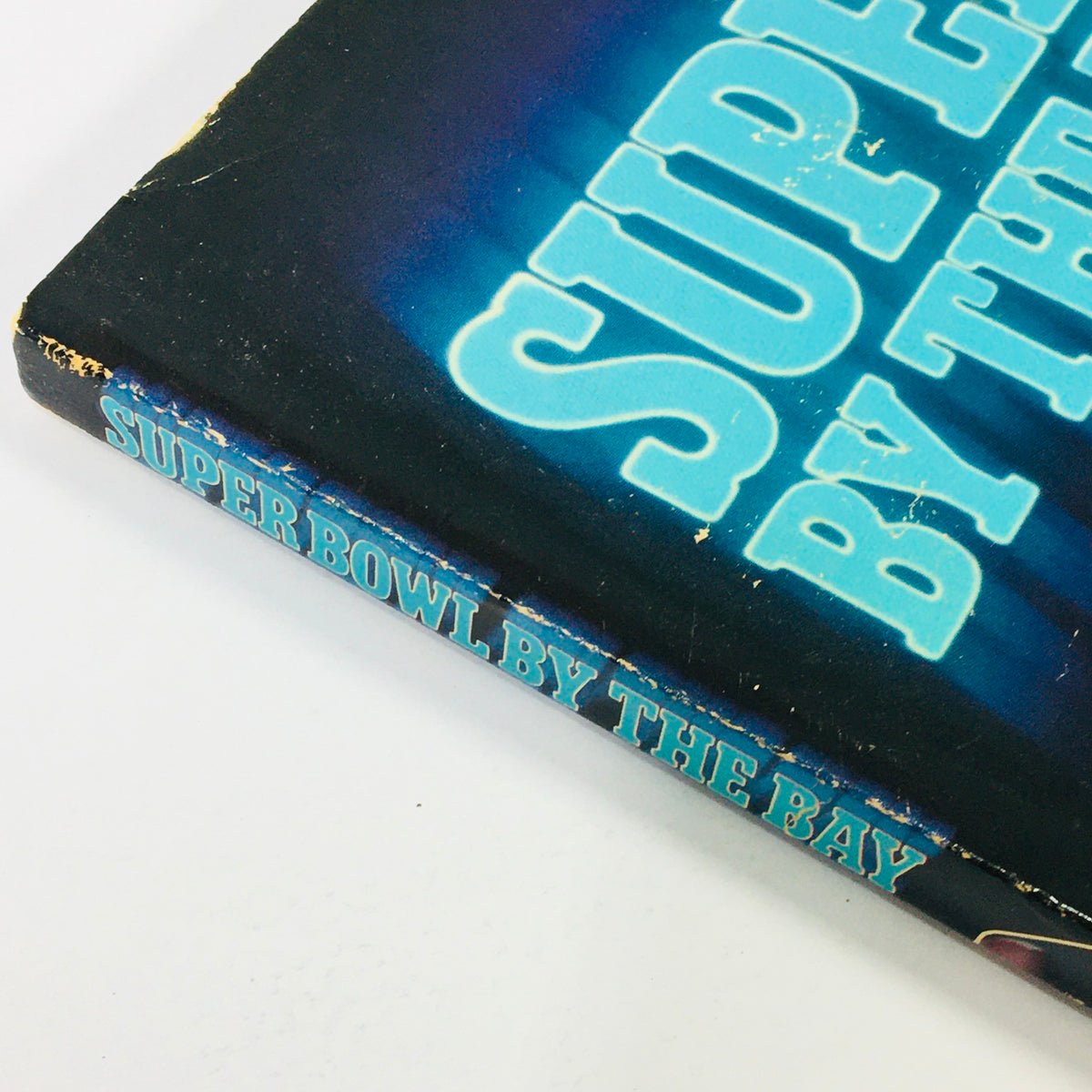 Side view of the VTG 1984 Official Super Bowl XIX Scenic Guide to San Francisco Bay, highlighting the title 'Super Bowl By the Bay' in bright blue text against a dark background.