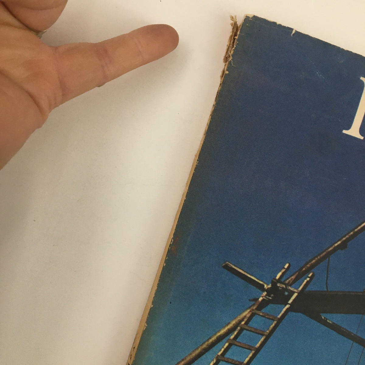 Close-up of the edge of Fortune Magazine July 1947 showing wear, with a hand pointing towards the binding.