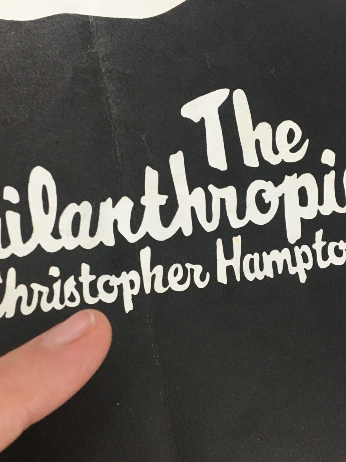 Close-up view of the title section of the 1970 May Fair Theatre Programme for The Philanthropist by Christopher Hampton, with a pointing finger for emphasis.