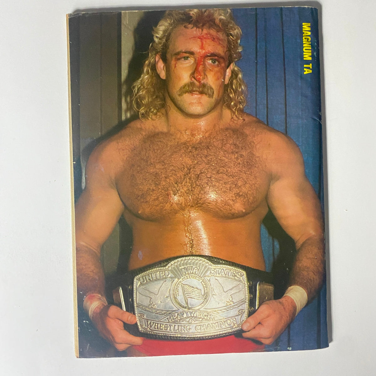 Cover image of Ringside Wrestling Magazine May 1986 featuring Magnum TA with a wrestling championship belt, showcasing his muscular physique and iconic look that captures the essence of 1980s professional wrestling.