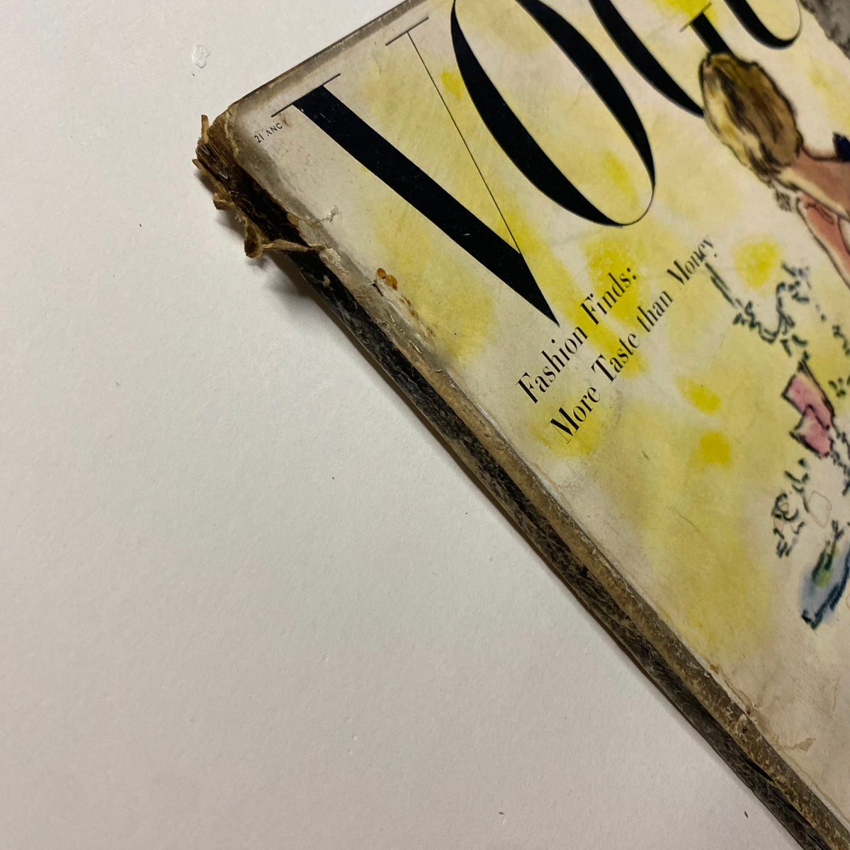 Close-up of the November 1, 1947 Vogue Magazine cover edge, displaying the vintage wear and charm of the issue featuring a fashion illustration by René Bouché, labeled 'Fashion Finds: More Taste than Money'.