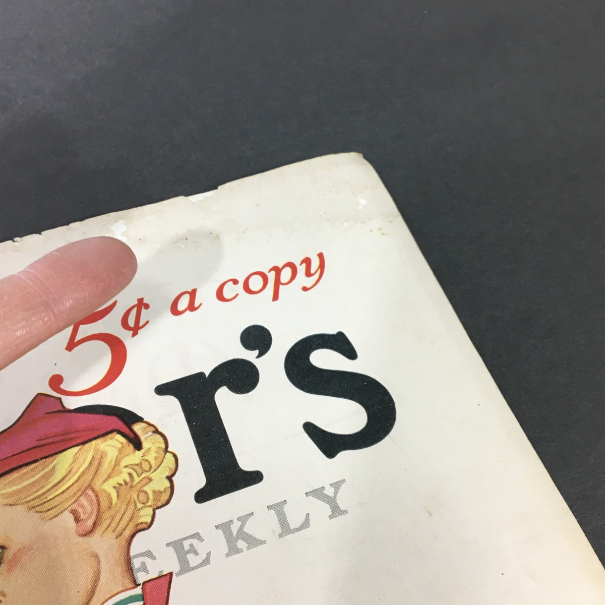 Detailed view of the top of VTG Collier's Magazine December 12, 1936, highlighting the '5¢ a copy' text with a finger pointing at the magazine cover's corner.