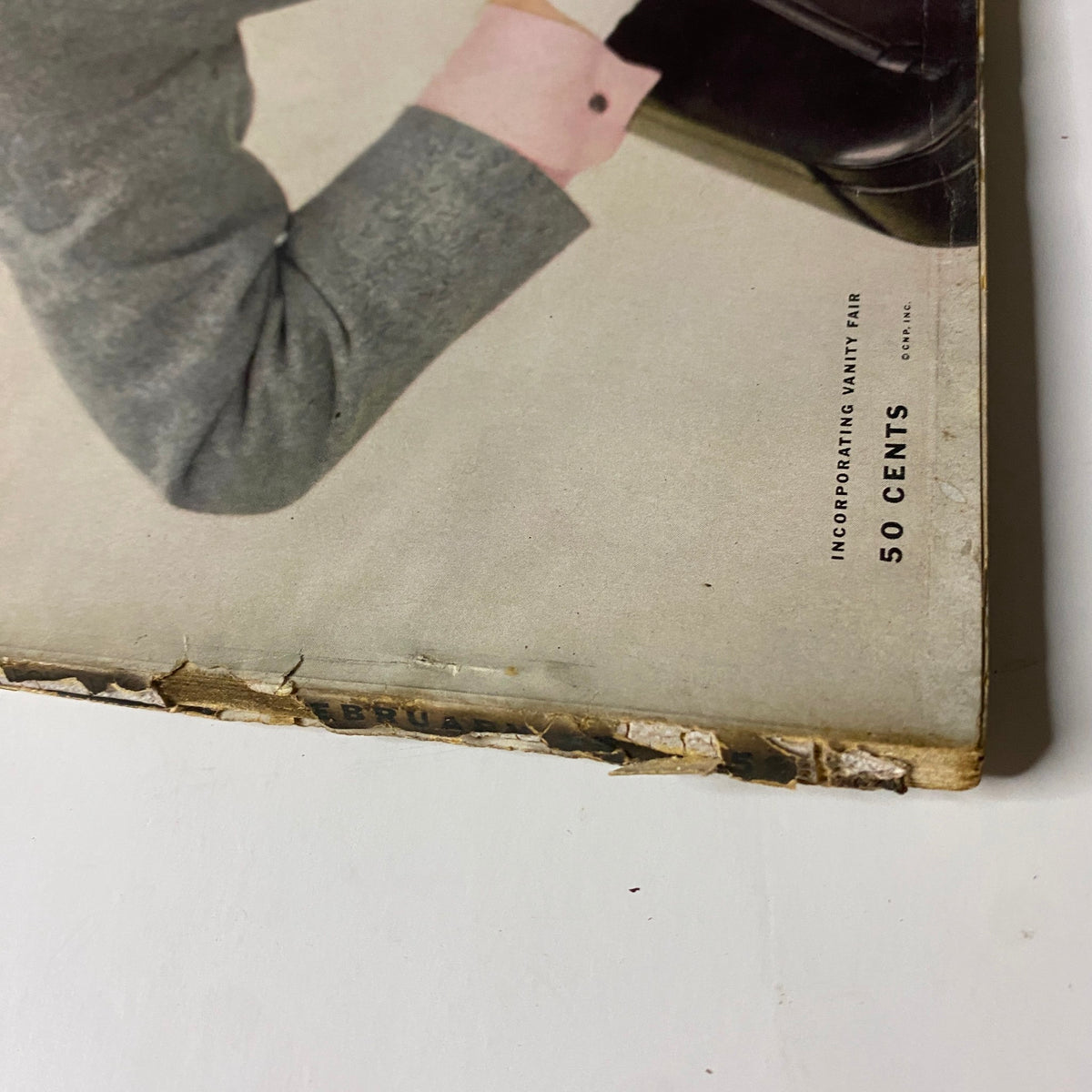 Bottom edge of Vogue Magazine February 15, 1952, highlighting wear and tear, reflective of its age. The visible title 'Vogue' emphasizes the magazine's collectible nature.