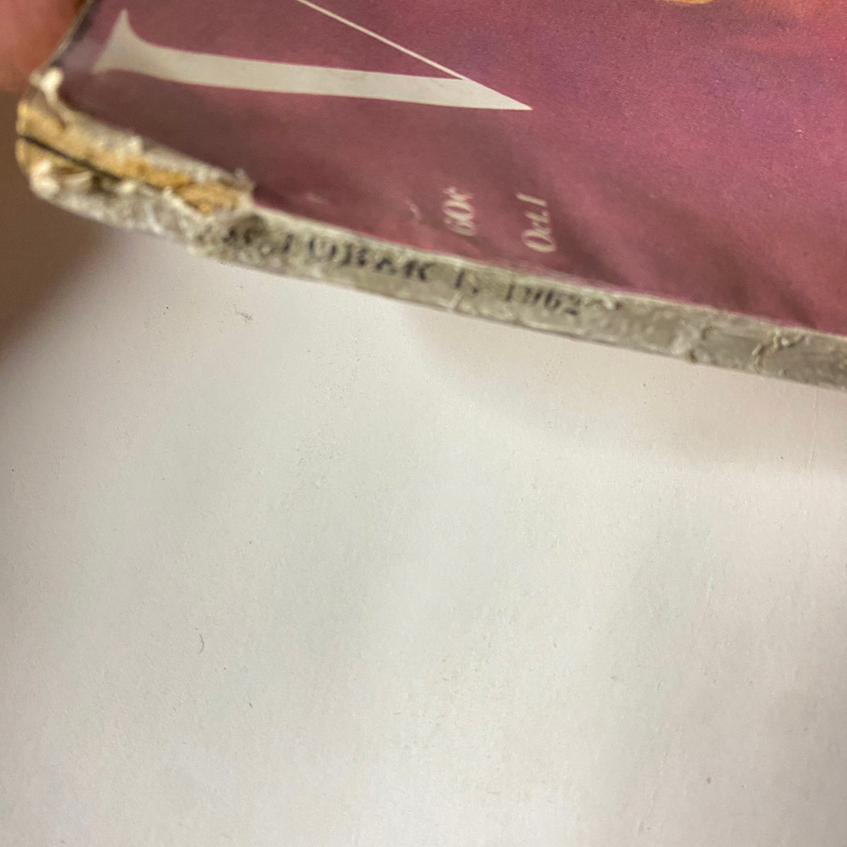 Condition detail of Vogue Magazine October 1, 1962 Tilly Tizzani Cover by Bert Stern showing age-related wear on the spine, indicative of its vintage status. 