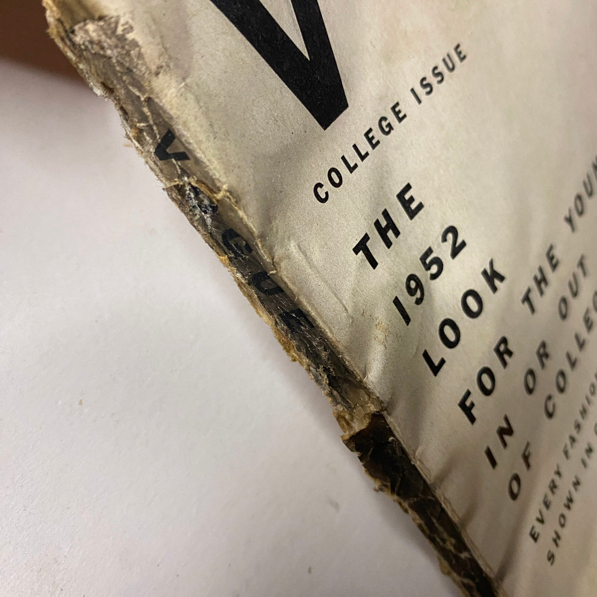 Side view of the Vogue Magazine August 15, 1952, displaying the College Issue title, featuring signs of vintage wear with frayed edges.