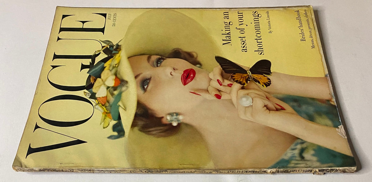 Side view of Vogue Magazine July 1957 cover showing model Joanna McCormick. The magazine emphasizes 'Making an asset of your shortcomings' and showcases mid-century fashion elegance.