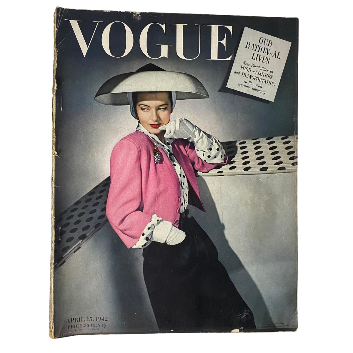 Cover of Vogue Magazine April 15, 1942 featuring 'Our Ration-al Lives' by John Rawlings, showcasing a model in a pink ensemble and large hat against a unique backdrop.
